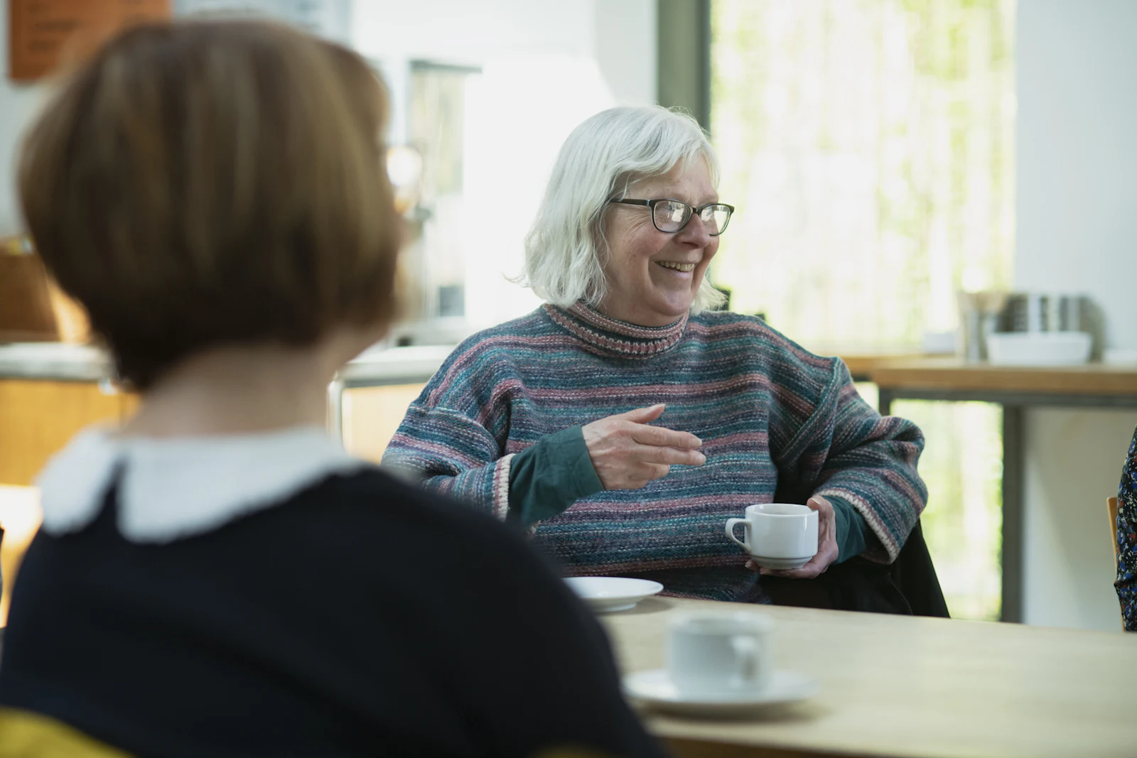 Two women talking over coffee at a table